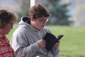 Momentum Camper reading Bible with leader